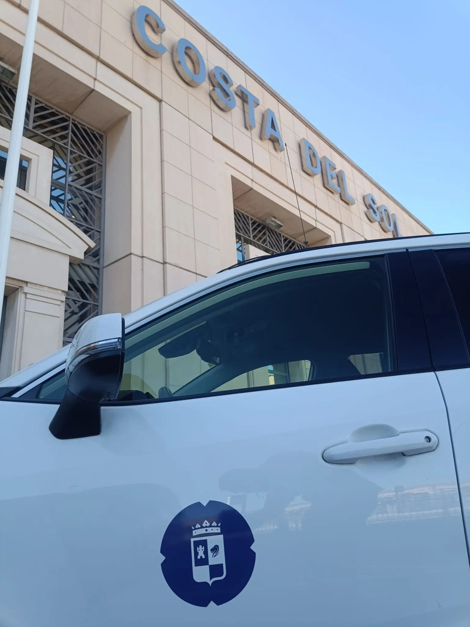 Door of the Torrox taxi with the municipal crest in front of the Costa del Sol sign at the Málaga Airport terminal