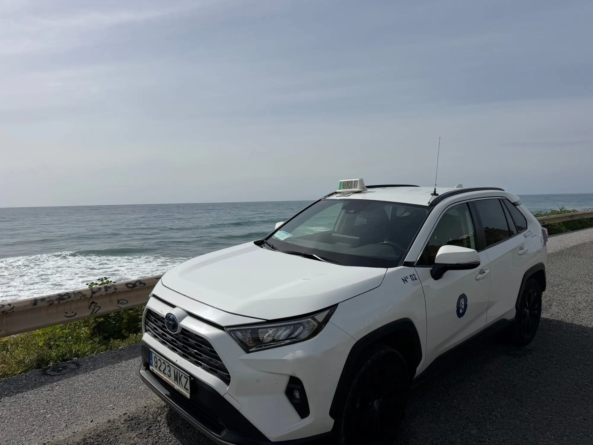Taxi aus Torrox an einer Küstenstraße mit Wellen