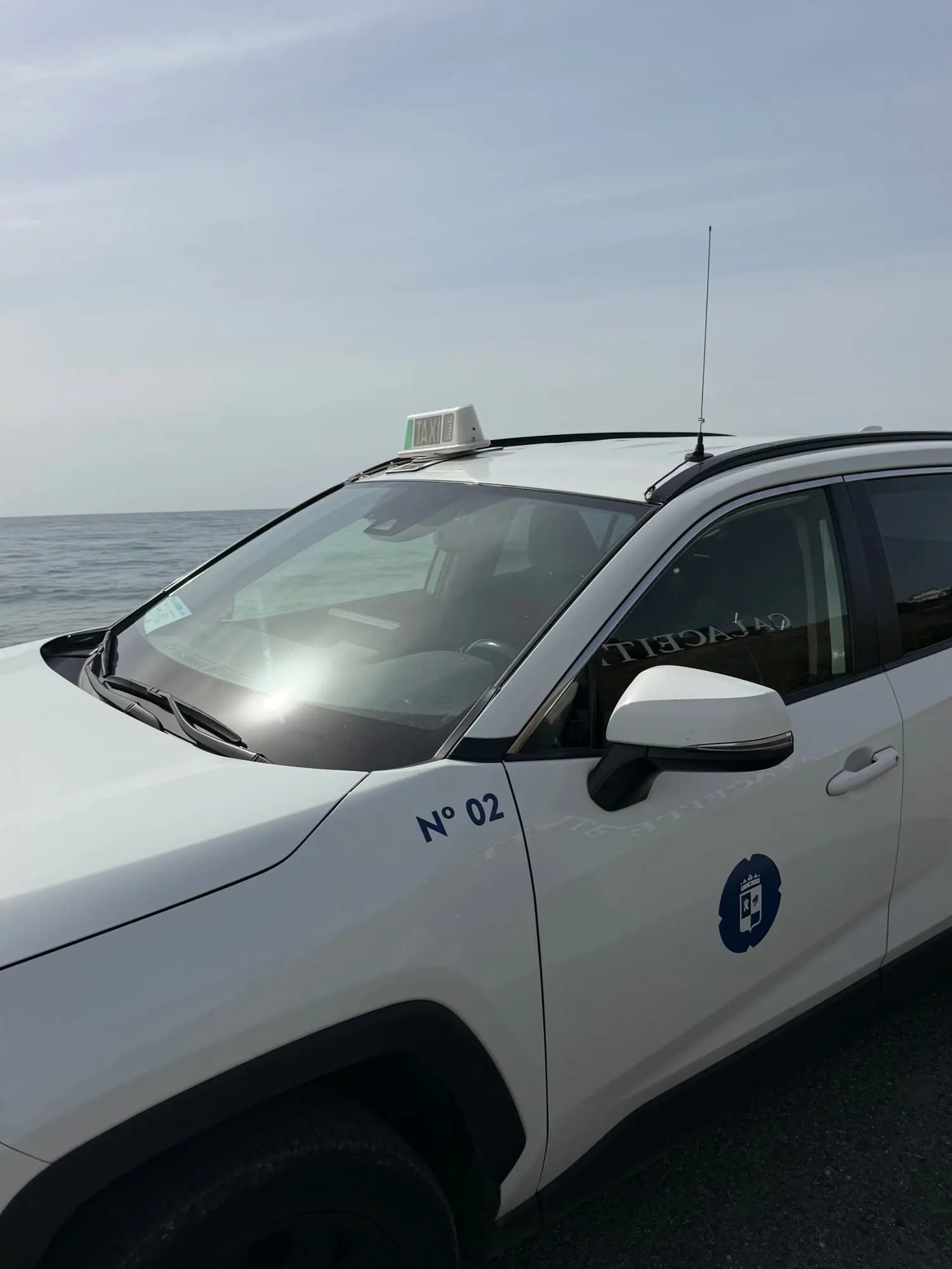 Taxi nº 02 de Torrox junto al mar con el escudo municipal en la puerta